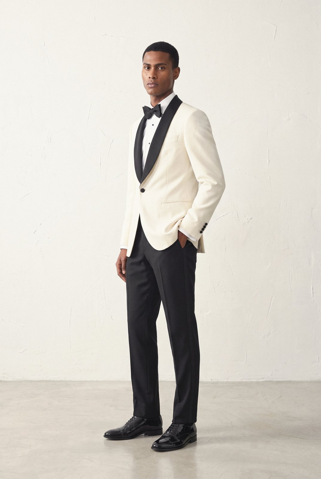 A man in an ivory dinner jacket, black trousers and a bow tie.